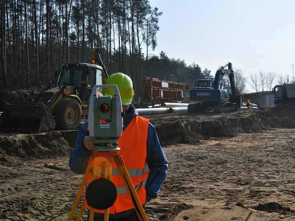 Site engineer surveying active infrastructure works